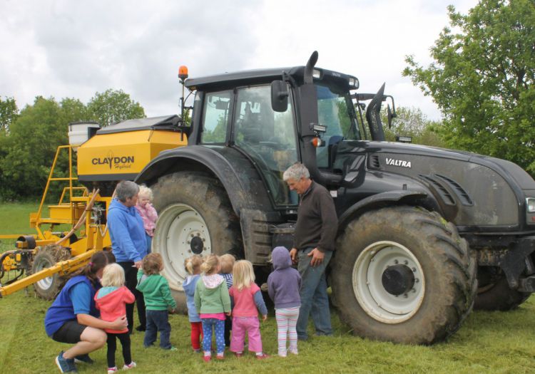 toddlers looking at tractor with farmer