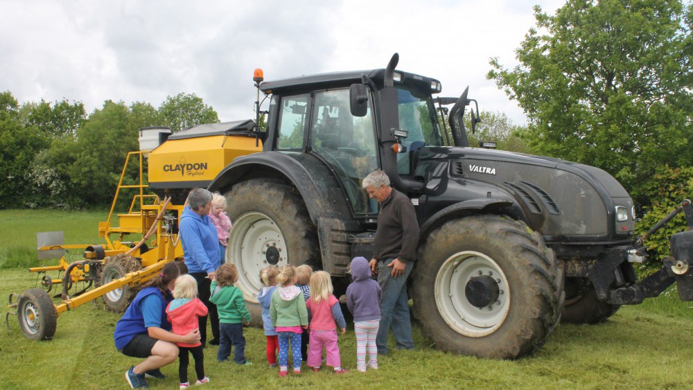 toddlers looking at tractor with farmer