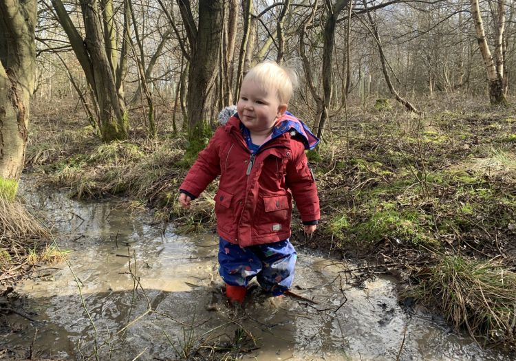 Baby playing in stream in woods