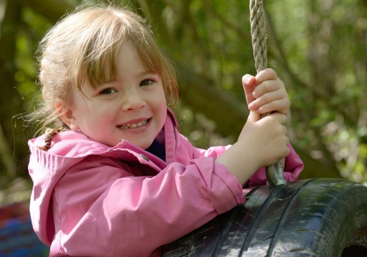 child playing on tyre swing
