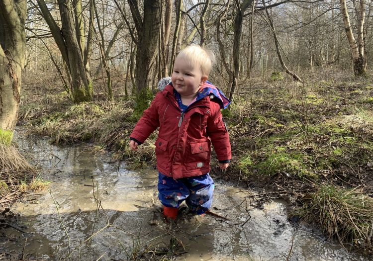 Baby playing in stream in woods